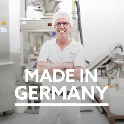Inscripción "Made in Germany" delante de entorno de producción con máquinas al fondo.