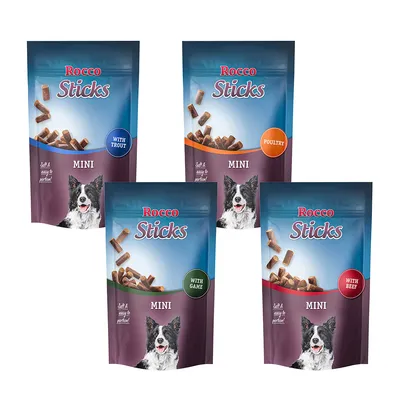 Cuatro bolsas de snacks Rocco Sticks Mini para perros, variedades visibles: with trout, poultry, with game y with beef. Texto visible: Soft & easy to portion! Imagen de perro en cada bolsa.