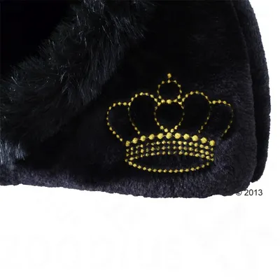 Detail čierneho plyšového materiálu s vyšitým zlatým motívom koruny na povrchu. Viditeľná štruktúra textilu a okraj s dlhším vlasom.