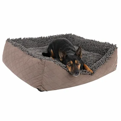 Hund liegt in einem grauen, gepolsterten Hundebett mit weicher Struktur und gestepptem Rand.