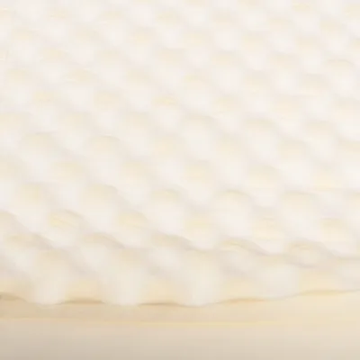 Nahaufnahme einer weissen, gepolsterten Oberfläche mit Wellenstruktur, möglicherweise Materialbeschreibung für ein Produkt.