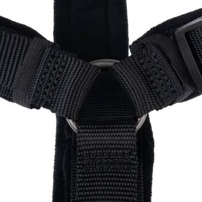 Close-up of a black harness system with metal ring and durable nylon straps, suitable for fastening or securing.