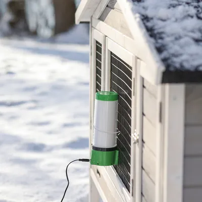 Elektrisk opvarmet vandskål med grønt låg, fastgjort til en udendørs indhegning i sneen.