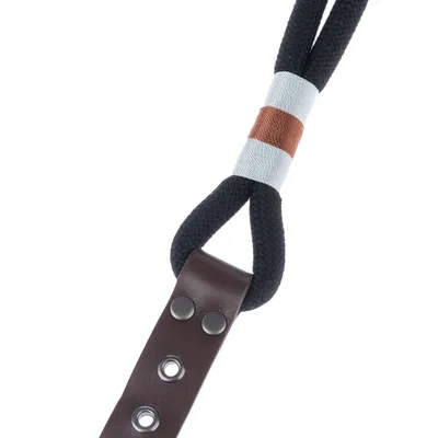 Close-up of a dog lead made of black rope with a brown leather handle and coloured wrapping in white and brown.