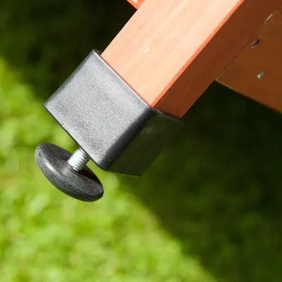 Close-up of an adjustable plastic foot attached to the bottom of a wooden furniture leg, showing height adjustment mechanism.