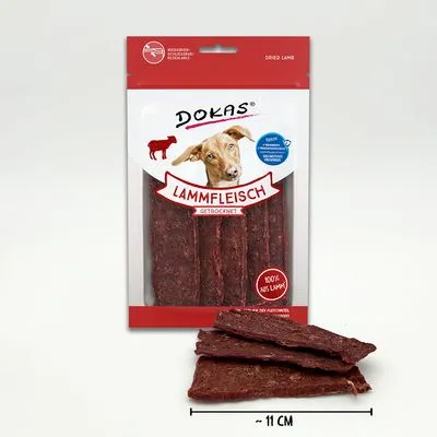 Dokas Lammfleisch gedroogd, verpakking met zichtbare lamsvleesrepen en afbeelding van een hond. Tekst: 100% aus Lamm, ~11 cm.