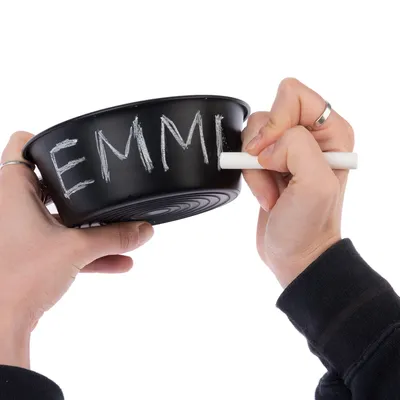 Musta kuppi, johon kirjoitetaan liidulla nimi 'EMMI'. Henkilö pitää liitua ja kirjoittaa kupin pinnalle.