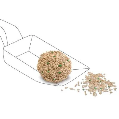 Klonter kattenbakvulling met beige korrels en enkele groene stukjes, gevormd tot een bal op een schep, met losse korrels ernaast zichtbaar.