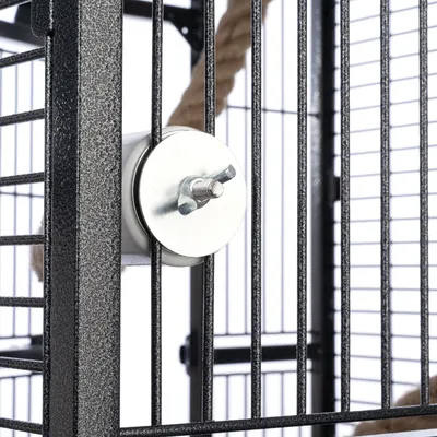 Close-up of a metal cage with wing screw for fastening. Background shows rope toy and grid structure.