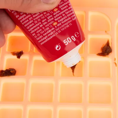 Rote Tube mit 50g Inhalt, Paste wird auf eine orangefarbene Silikonmatte mit Vertiefungen gedrückt.