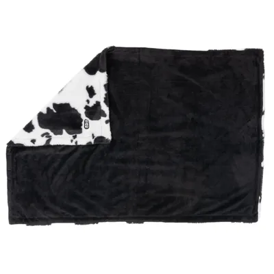 Schwarze Decke mit Kuhfellmuster auf der Rückseite, weiches Material. Sichtbares Etikett mit Logo Trixie.