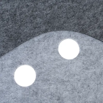 Gros plan sur une surface en feutre gris clair et foncé avec deux trous ronds visibles. Matériau textile, détails de texture et découpes circulaires.