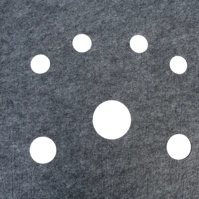 Tapis en feutre gris avec six trous ronds de tailles différentes disposés en cercle autour d’un trou central plus grand. Matériau visible : feutre.