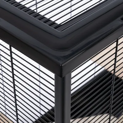 Close-up of a black metal cage corner showing vertical and horizontal bars with a reinforced plastic frame.