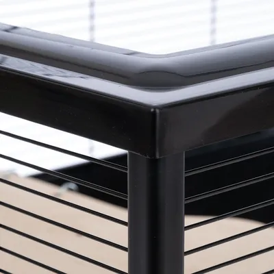 Detaljevisning af sort metalramme med vandrette gitre, egnet til bure eller indhegninger.