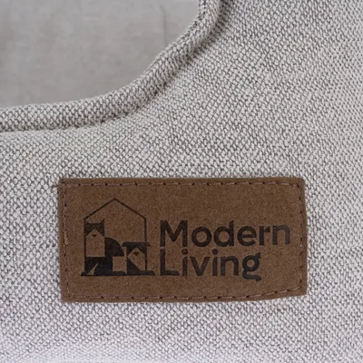 Modern Living. Logo auf einem braunen Lederetikett, genäht auf grauem Stoff.