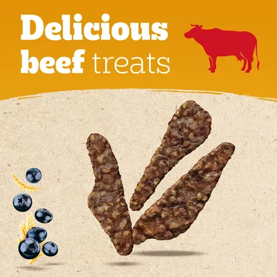 Tekst: Delicious beef treats. Trzy kawałki przysmaku wołowego, obok widoczne jagody i kłosy zboża, grafika czerwonej krowy.