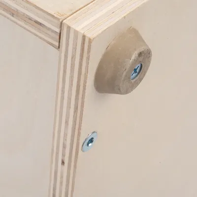 Close-up view of a wooden construction with screws and a rubberised base.