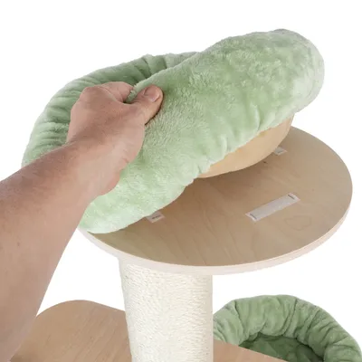Hand showing removable green plush cushion on a wooden platform of a scratching post with hook-and-loop fastener.