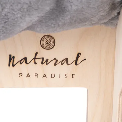 Natural Paradise Logo auf hellem Holz mit Pfotenmotiv und grauem Stoff oben sichtbar.