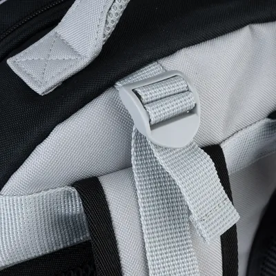 Gros plan sur une sangle réglable en tissu gris avec boucle en plastique sur un sac, coutures visibles. Aucun logo ou texte apparent.