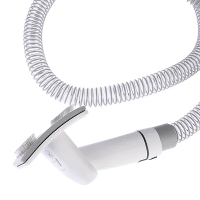 White grooming attachment with brush head and flexible spiral hose, suitable for connection to a vacuum cleaner.