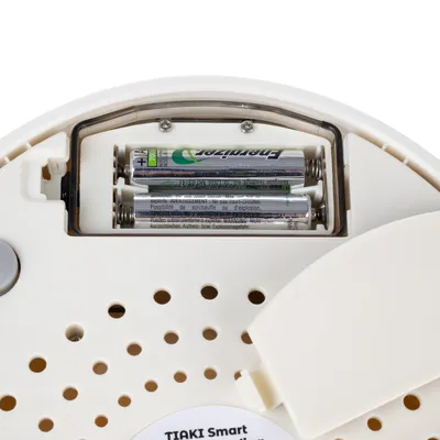 Battery compartment of the Tiaki Smart device with inserted AA batteries. Safety warnings visible.