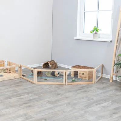 Recinto in legno con pareti a griglia, adatto per piccoli animali. Include tunnel in legno, casetta e lettiera. Recinto su pavimento in laminato in una stanza luminosa con finestra e piante.