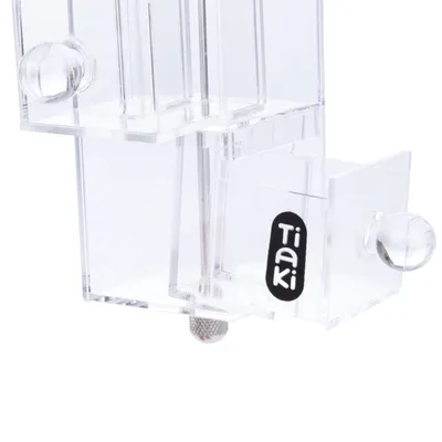 Boîte transparente en plastique avec boutons ronds et logo Tiaki visible sur le côté.