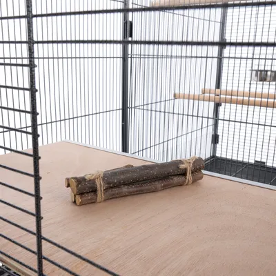Bastoncini di legno legati con una corda, posizionati su una piattaforma di legno in una gabbia di metallo.