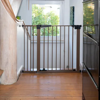 Brunt skyddsgaller av metall, monterat mellan två väggar på ett trägolv. Lämpligt för att säkra trappor eller passager.