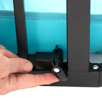 Nahaufnahme eines schwarzen Verriegelungsmechanismus mit einer Hand, die den Hebel drückt. Hintergrund aus hellblauem Stoff.