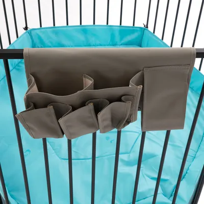 Organizer aus grauem Stoff mit mehreren Taschen, befestigt an einem schwarzen Metallgitter. Hintergrund zeigt eine blaue gepolsterte Unterlage.