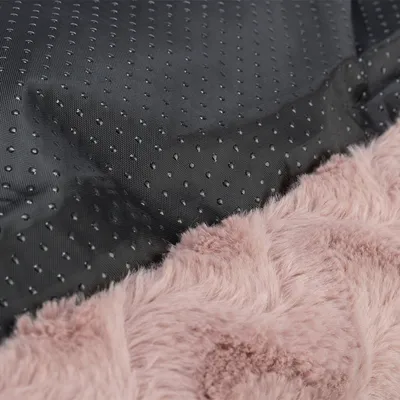 Nahaufnahme eines Produkts mit rutschfester Unterseite aus schwarzem Material und weicher rosa Plüschoberfläche.