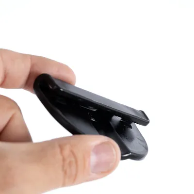 Main tenant une pièce en plastique noir, vue rapprochée sur l’objet sans marque ni texte visible.