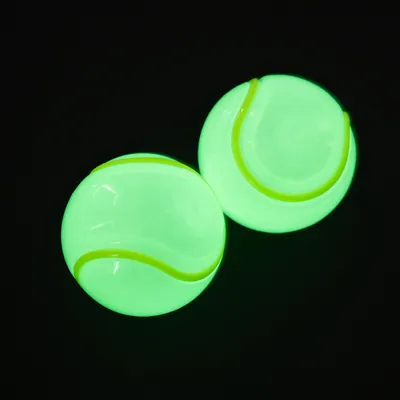 Два ярко-зелёных мяча с теннисным дизайном на чёрном фоне.