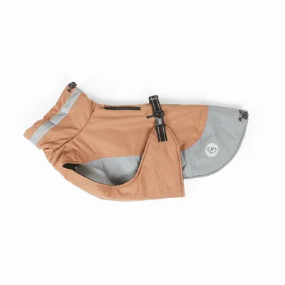 Manteau pour chien beige et gris avec bandes réfléchissantes, boucle noire réglable et écusson rond NT visible sur le côté arrière.