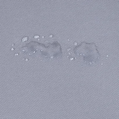 Nahaufnahme eines grauen, wasserabweisenden Stoffes mit Wassertropfen auf der Oberfläche.