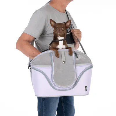 Sac de transport rigide gris et blanc avec filet, porté à l’épaule, petit chien à l’intérieur, logo Trixie visible sur le côté du sac.