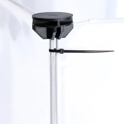 Detailaufnahme eines schwarzen Kunststoffclips mit Kabelbinder zur Befestigung an einer transparenten Wand.
