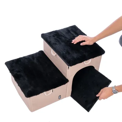 Treppenförmiges Möbelstück mit drei Ebenen, schwarzem Plüschbezug und beige Stoffbasis. Hand zeigt abnehmbare obere Abdeckung mit integriertem Stauraum.