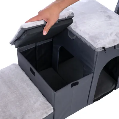 Hand öffnet gepolsterten Deckel einer grauen Haustierbox mit mehreren Fächern und weicher Innenausstattung.