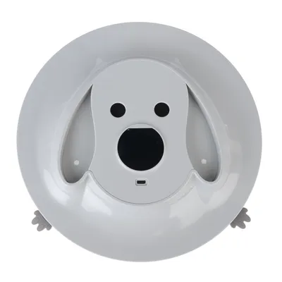 Rundes weisses Gerät mit Hundegesicht-Design, zwei schwarzen Sensoren, einem zentralen Display und USB-Anschluss. Seitlich graue Pfotenakzente sichtbar.