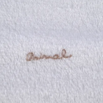 Inscription brodée « animal » sur tissu blanc à texture douce, type polaire ou serviette.