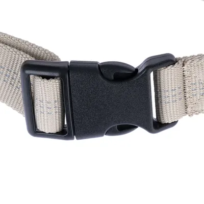 Gros plan sur une boucle en plastique noir avec sangle beige tissée, système de fermeture à clip pour collier ou harnais.