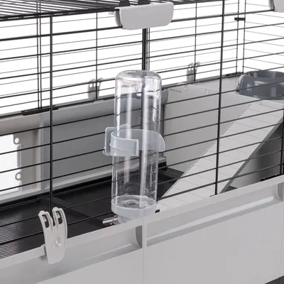 Trinkflasche aus transparentem Kunststoff mit Halterung, befestigt an einem Metallkäfig. Geeignet für Kleintiere wie Kaninchen oder Meerschweinchen.