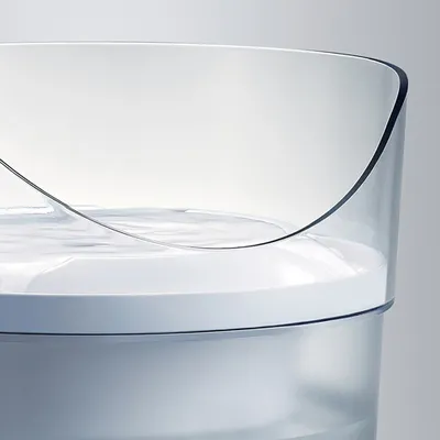 Transparenter Wasserbehälter mit geschwungenem Rand, gefüllt mit klarem Wasser.