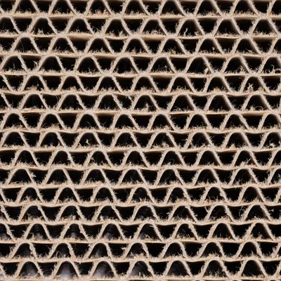 Gros plan sur des couches de carton ondulé, montrant la structure en vagues du matériau. Convient pour illustrer le matériau utilisé dans certains griffoirs ou accessoires pour animaux.
