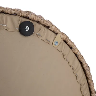 Détail du dessous d’un panier pour animaux en tissu beige avec rebord tressé, fixations métalliques et patin antidérapant visible.
