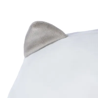 Detailní záběr na bílý polštář s šedým plyšovým rohem ve tvaru zvířecího ucha.